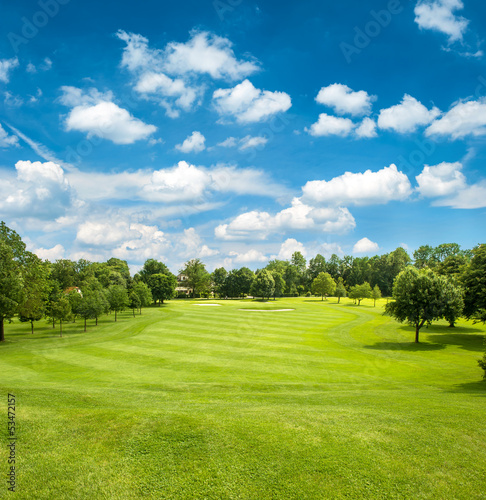 Obraz na płótnie canvas Zielone pole golfowe i błękitne niebo pochmurne