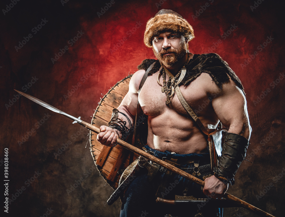 Nude Handsome Northern Barbarian With Naked Torso And Muscular Build Poses Holding A Spear In