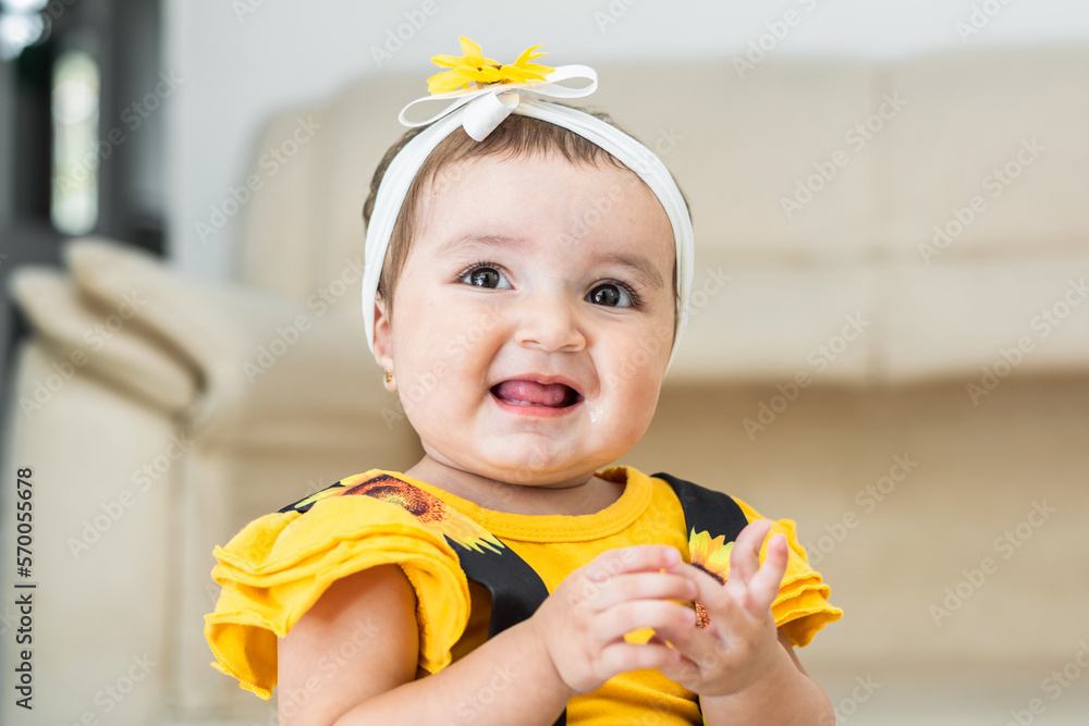Beautiful Latina Baby Very Happy Smiling And Showing Her Tongue She Is Wearing A Yellow Dress