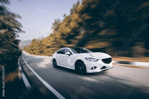 White car speed driving on asphalt road at daytime