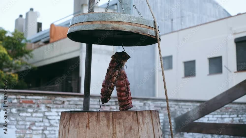 Big Pieces Of Pork Meat On Ribs Tied And Hanged Above Big Wooden Barrel