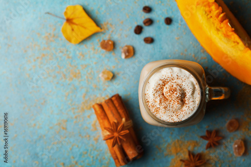 Pumpkin spiced latte or coffee in cup decorated cinnamon on turquoise vintage table top view. Autumn, fall or winter hot drink. Cozy breakfast.