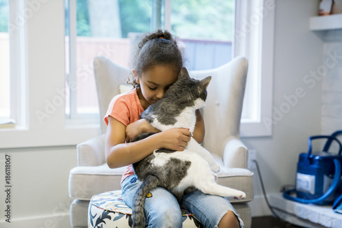 Girl hugging cat in living room 