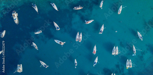 Aerial view of many anchoring yacht in open water.