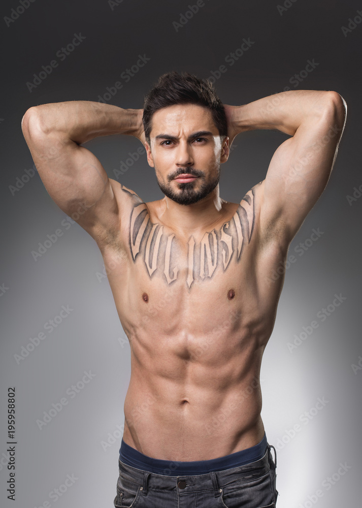 Waist Up Portrait Of Serious Muscular Man With Naked Upper Body Holding Hands On Back Of His