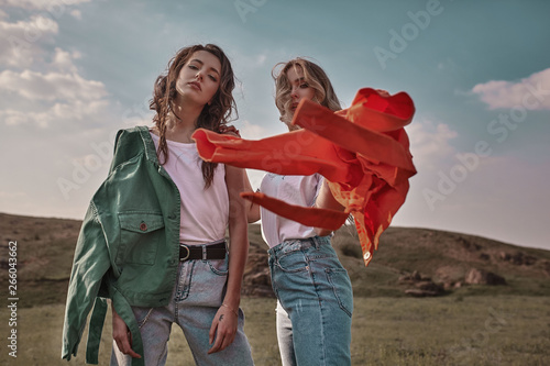 High fashion portrait of two stylish beautiful woman in trendy jackets and jeans posing outdoor. Vogue style.