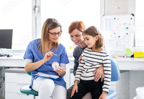 A small girl, mother and dentist in surgery, dental checkup.