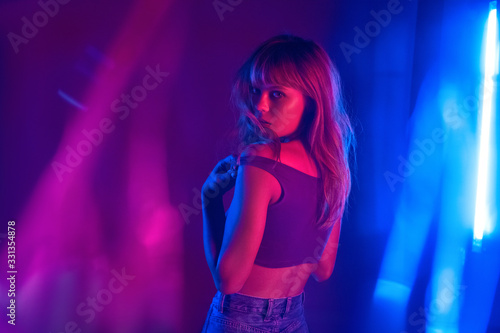 Sexy sensual fashion attractive young 20s girl model beautiful blond hair at purple studio background. Hot trendy stylish woman beauty face look at camera stand in neon violet light concept. Portrait.