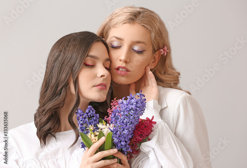 Beautiful young women with hyacinth flowers on light background