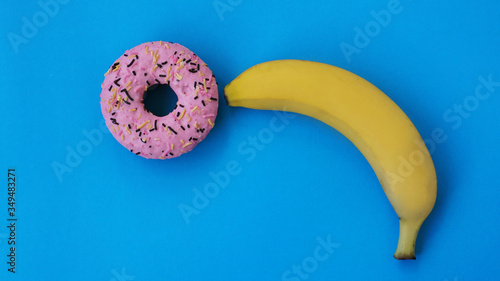 Sweet donut and banana on blue color background. Sex and Erotic concept