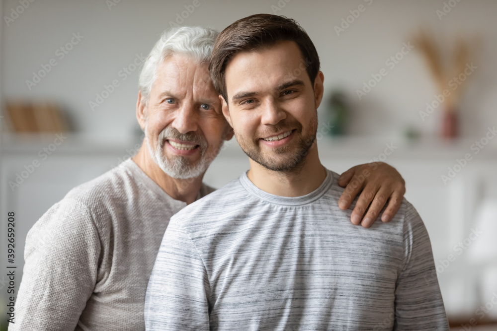 Head Shot Portrait Smiling Mature Father And Adult Son Hugging Standing Posing For Photo At