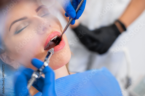 Dentist makes anesthetizing injection within patient`s mouth. Close up of Injection with anesthesia performed by doctor