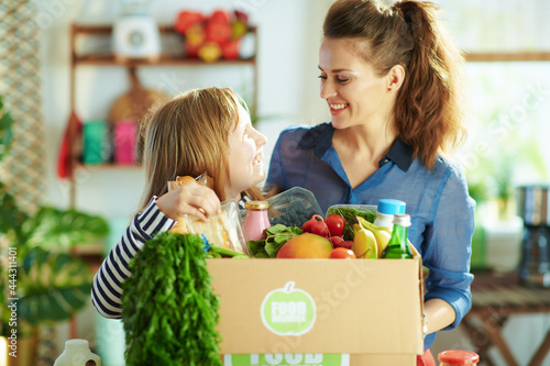 happy young mother and child with food box in kitchen