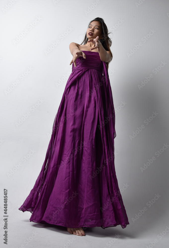 Full Length Portrait Of Pretty Brunette Asian Girl Wearing Purple Flowing Gown Standing Pose In