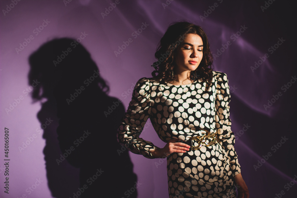 Beautiful Brunette Fashion Model In Polka Dot Dress Posing On A Lilac Background Shadow And