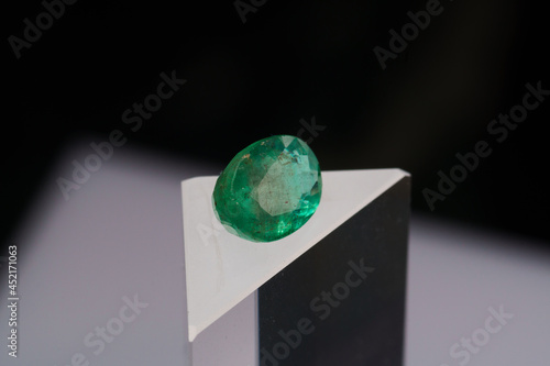 Natural gemstone green emerald on a stand on a black background