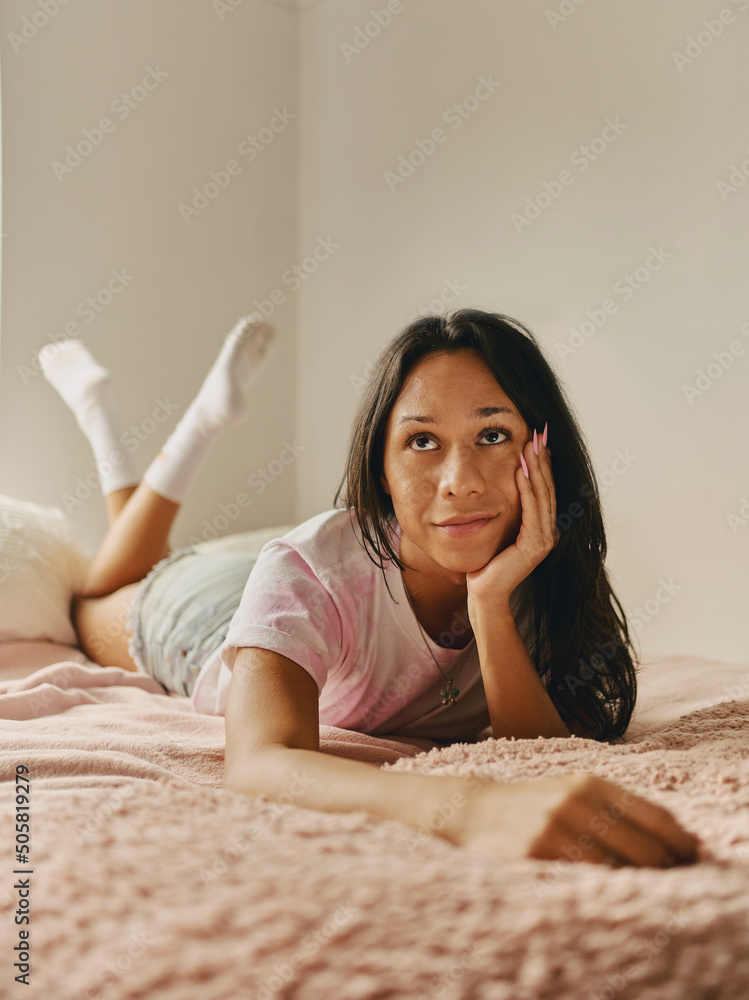 Joven transgénero latina pensativa posando con la mano en el rostro en su habitación Stock Photo