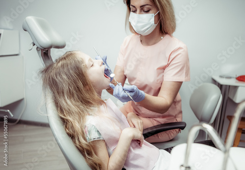 Sweet little girl in the dental chair. The dentist examines the teeth of the child's patient. Pediatric dentistry