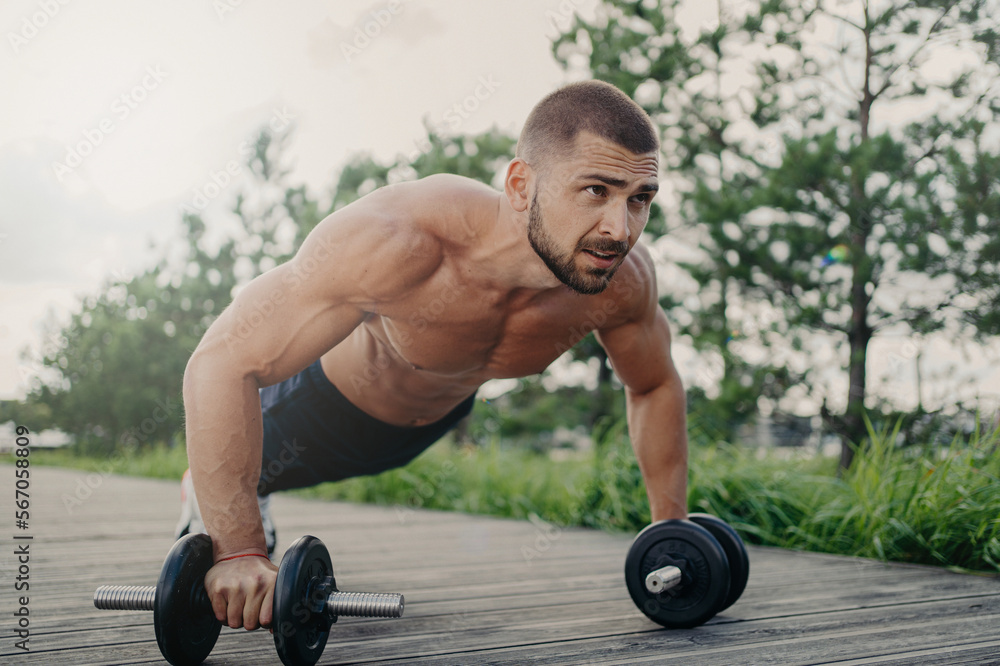 Muscular Male Bodybuilder Does Push Up With Barbells Stands In Palnk Pose With Naked Body