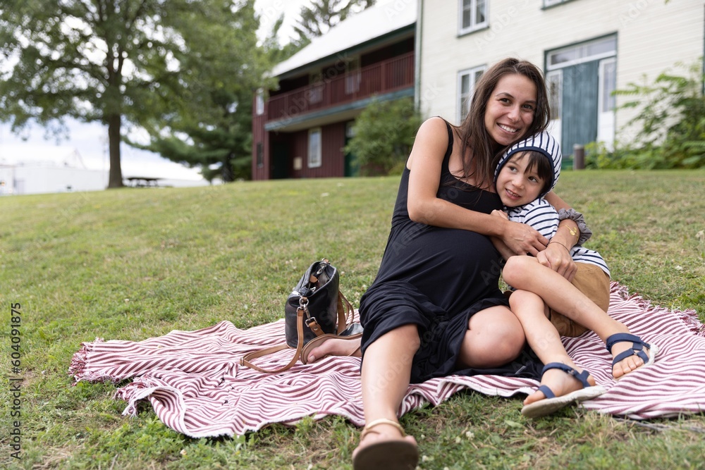 Pregnant Mother Holds Uninterested Son While Having A Picnic Outdoors