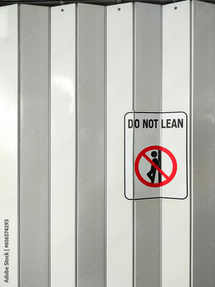 No Leaning Sign Label On Surface Of White And Gray Steel Folding Wall