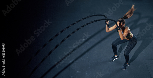Effective Workout with a rope. Sportswoman trains in the functional training gym, performing crossfit exercises with a battle rope