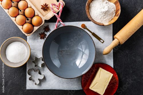 baking, cooking and christmas concept - close up of ceramic bowl, molds, rolling pin and ingredients on black table top