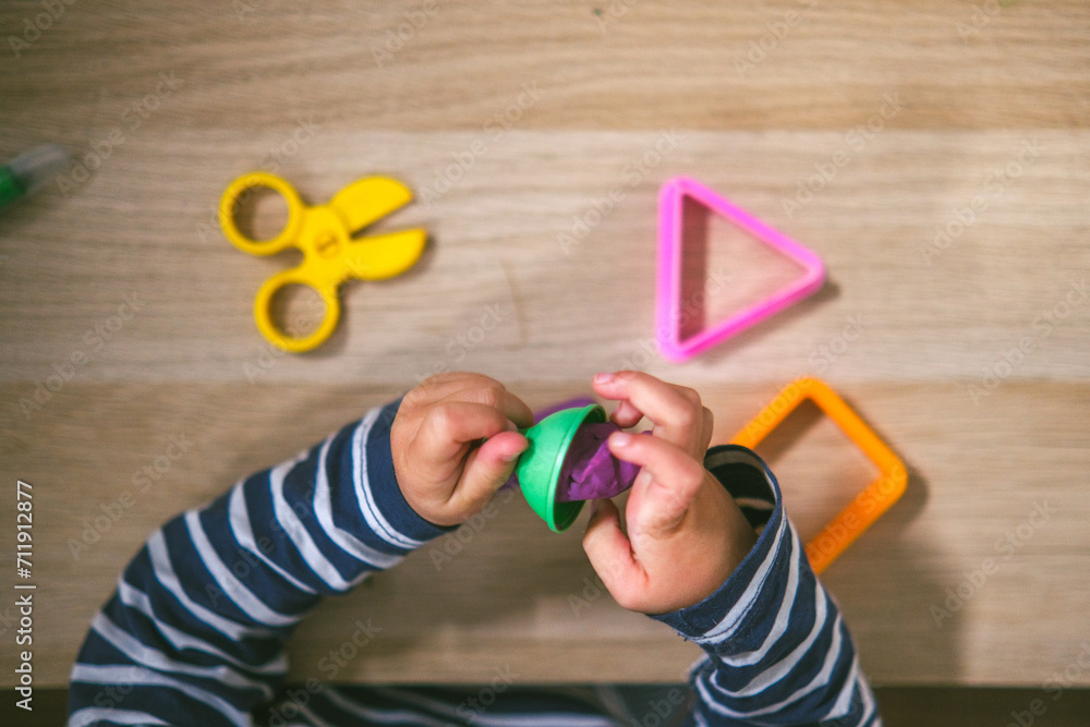 Foto de Manos de niña de 2 años jugando con plastilina casera y moldes