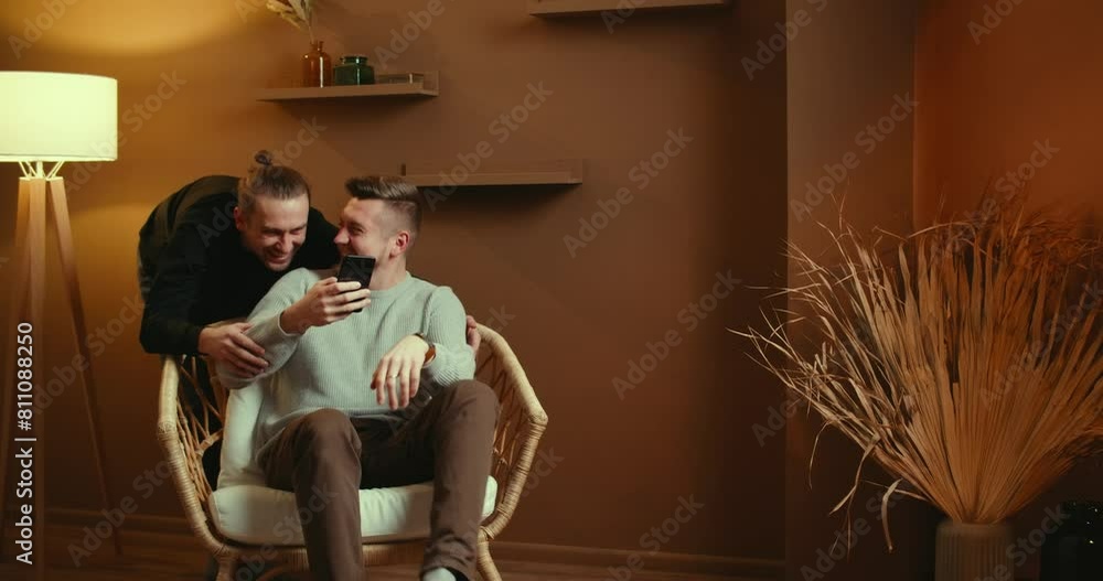 Cute Male Gay Couple Spend Time Sitting Chair Floor Use Smartphone Browse Online Laughing
