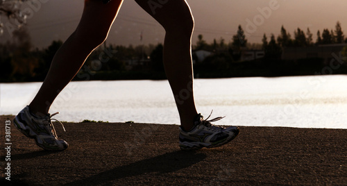 Tapeta ścienna Kobieta jogging wzdłuż rzeki o zachodzie słońca