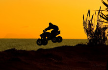 Quad Bike Jumping On Beach At Sunset In Spain