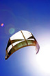 kite surfers kite flying in the dark blue sky with sun beaming o