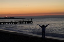 Sea Sunrise And Silhouette Of Girl With Seagulls