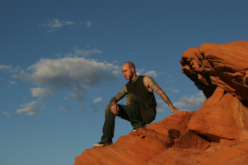 Wall Mural - tattooed man sitting on the red rocks