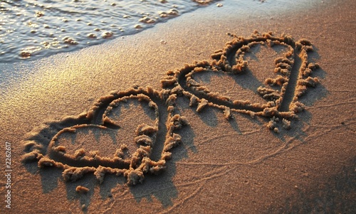 Fototapeta na wymiar two hearts on sand
