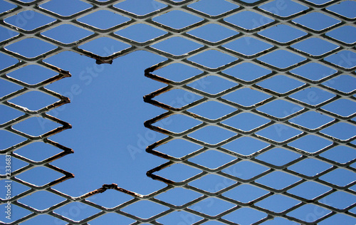 hole in fence off centre with blue sky © SammyC