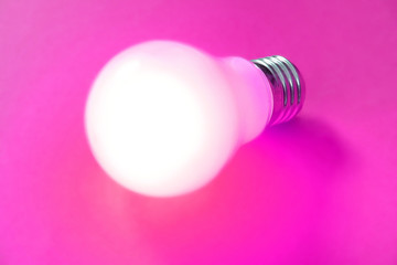 illuminated lightbulb on magenta background