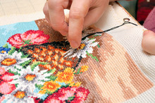A beautifully completed cross stitch project with vibrant threads and a needle