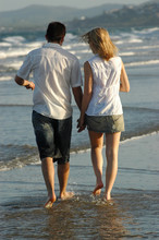Couple Walking On Waters Edge At Beach