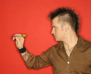 Caucasian man with mohawk throwing dart.