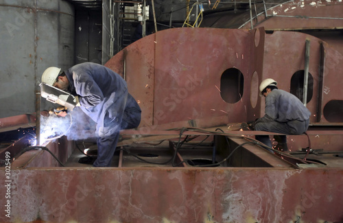 Fotomural Welders with protective mask welding metal at double bottom ship in a shipyard
