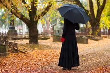 Woman In Mourning At Cemetery In Fall