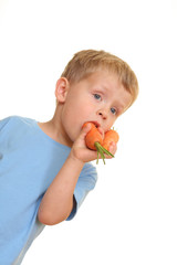 Wall Mural - three years old boy eating fresh carrot isolated on white