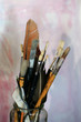 A collection of artist's brushes and tools in a glass jar