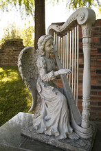 A Statue Of An Angel Playing A A Large Floor Harp.