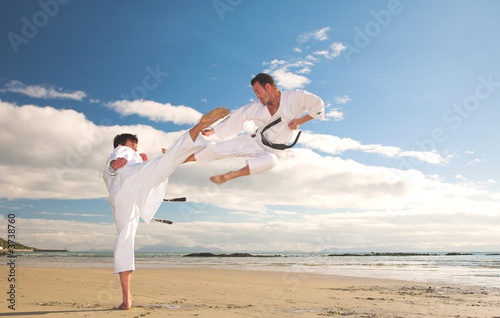 Naklejka samoprzylepna Młodych dorosłych mężczyzn uprawiających karate na plaży