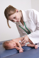 Young female doctor performing an examination on a newborn baby.