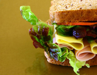 Wall Mural - wholebread sandwich with ham and cheese on brown background