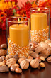 A candle in an autumn setting with corn and nuts