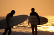 Two surfers at the beach at sunset